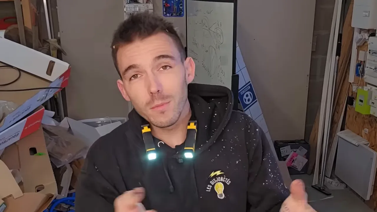 Présentateur portant une lampe tour de cou jaune (Caterpillar) autour du cou avec deux éclairages allumés, atelier en arrière‑plan