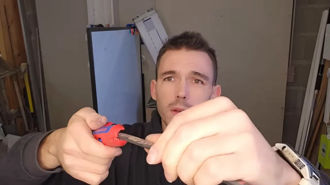 Électricien utilisant un dénude-câble rouge KNIPEX pour fendre la gaine d'un câble