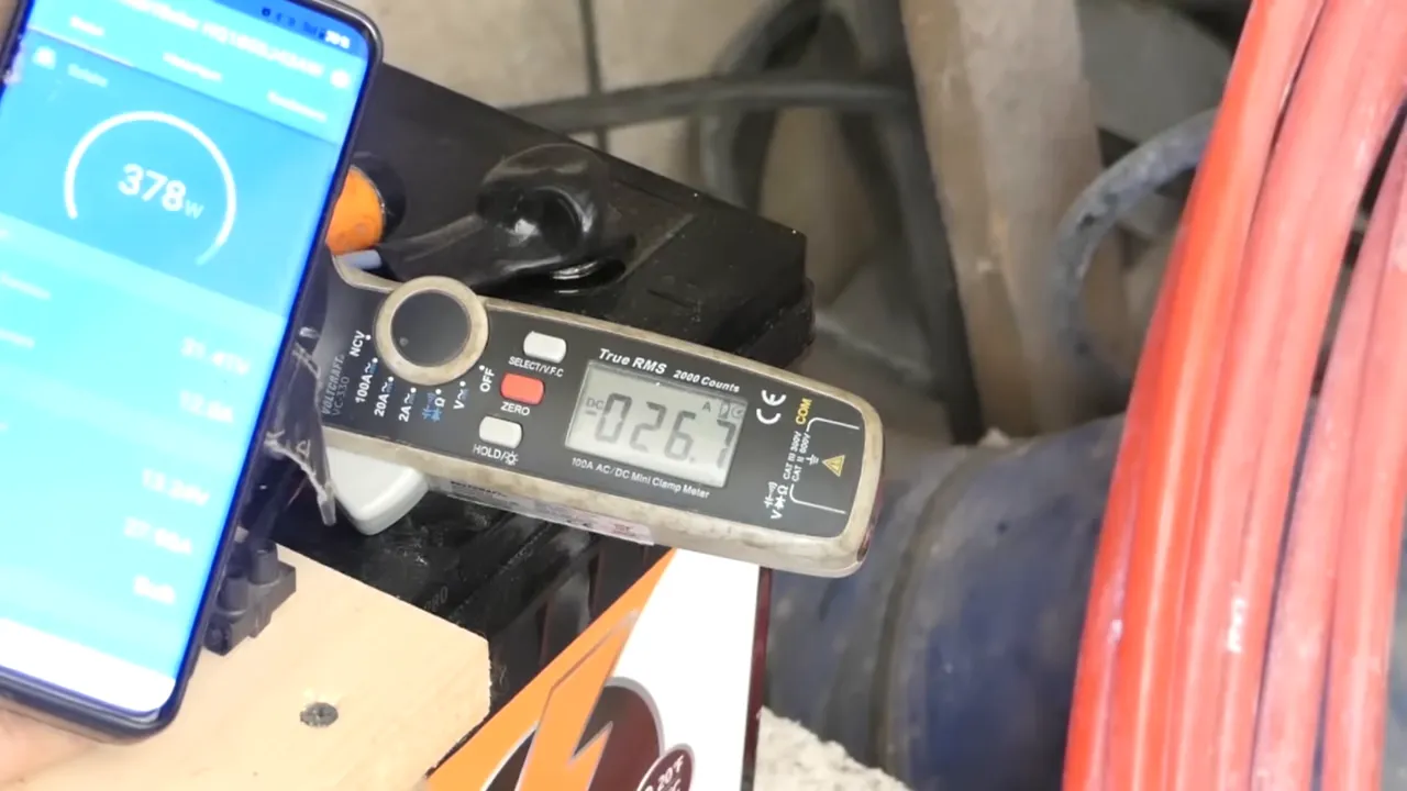 écran du téléphone montrant 378 W et pince ampèremetrique affichant 26,7 A