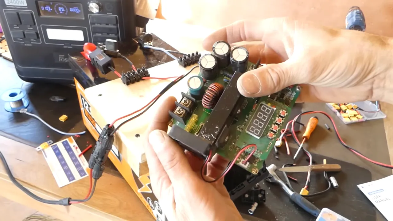 Module boost DC-DC tenu en main montrant inductance, condensateurs et afficheur — vue nette