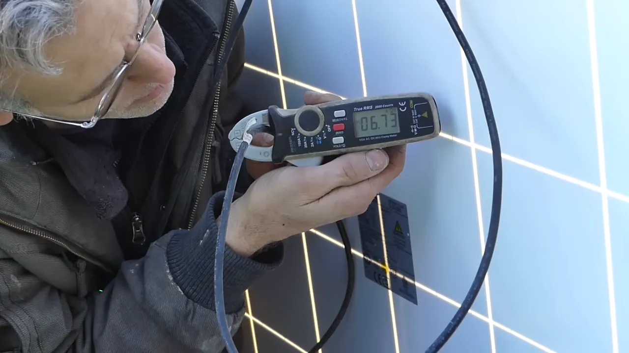 Pince ampèremetrique affichant 6.73 ampères lors de la mesure d'un panneau solaire