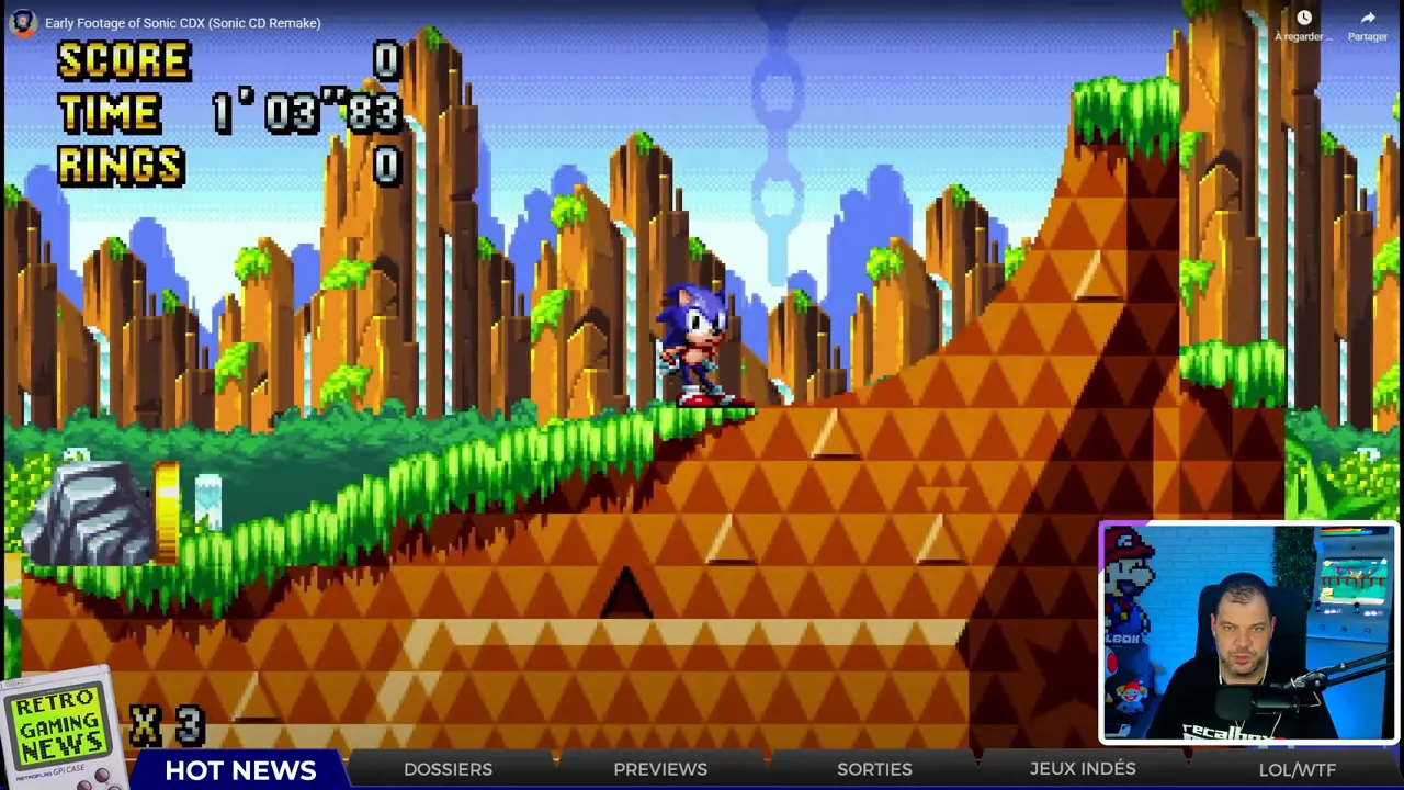 Capture d'écran Sonic en 2D sur une zone herbeuse avec l'interface score/temps et petit encart du présentateur