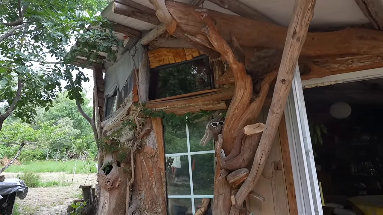 Façade de maison autoconstruite avec bois brut, fenêtre et montants en branches