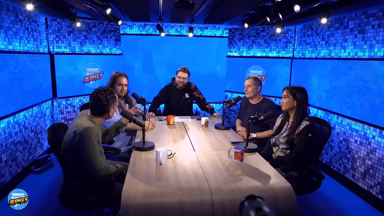 Plan large de l'équipe réunie autour d'une table dans un studio aux écrans bleus