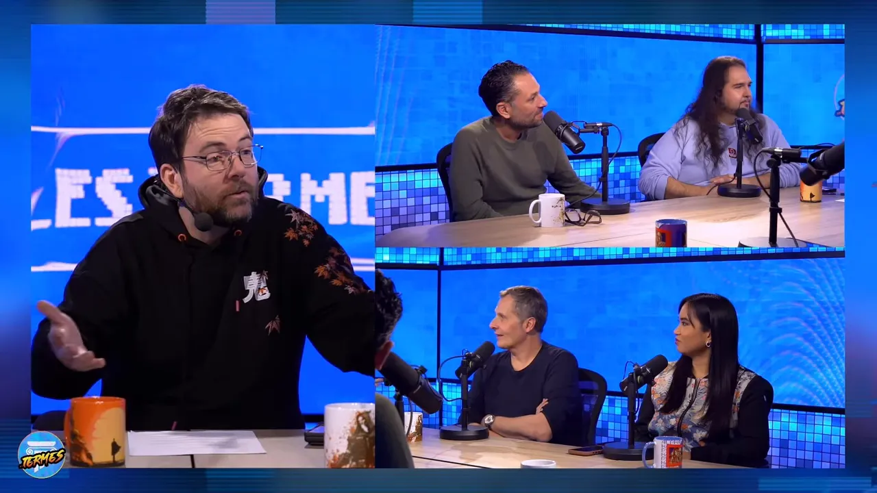 Intervenants d'une table ronde en train de discuter, l'un fait un geste explicatif, fond bleu net