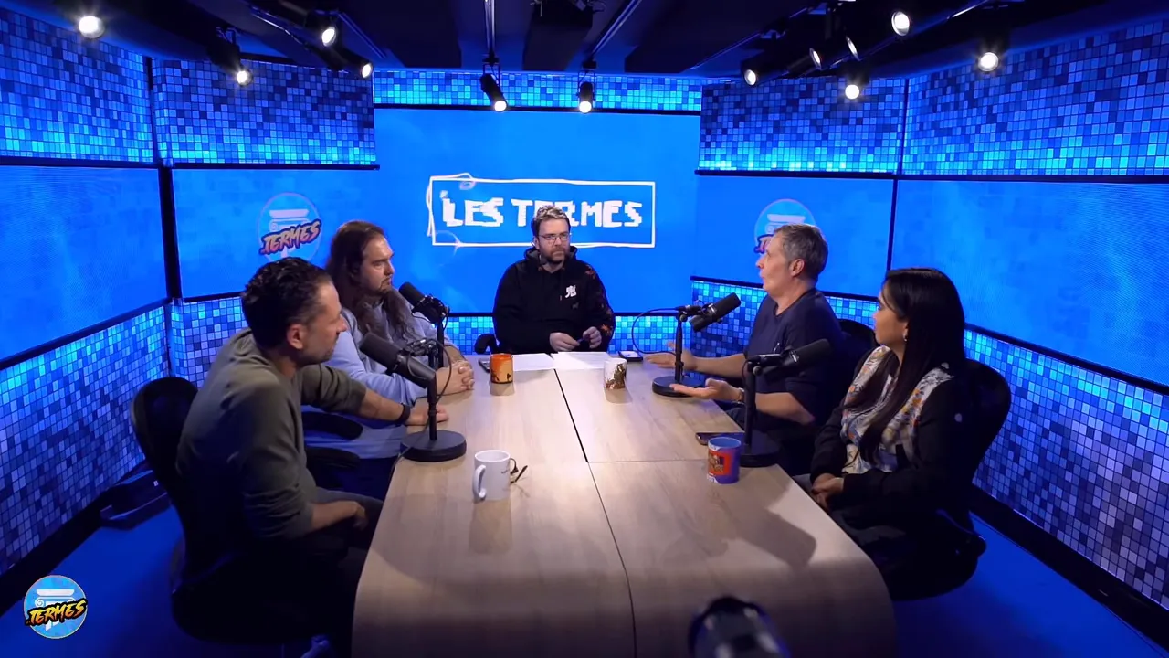 plan large du plateau Les Termes montrant cinq intervenants autour d'une table et le logo lumineux au centre