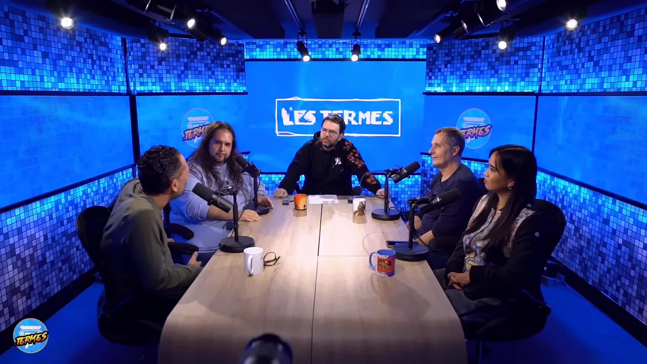 Plateau Les Termes en plan large montrant l'équipe autour d'une table avec le logo en fond
