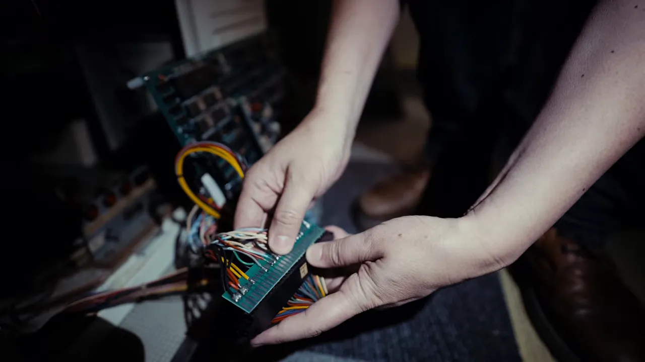 Mains posant une PCB d’arcade et connectant des câbles