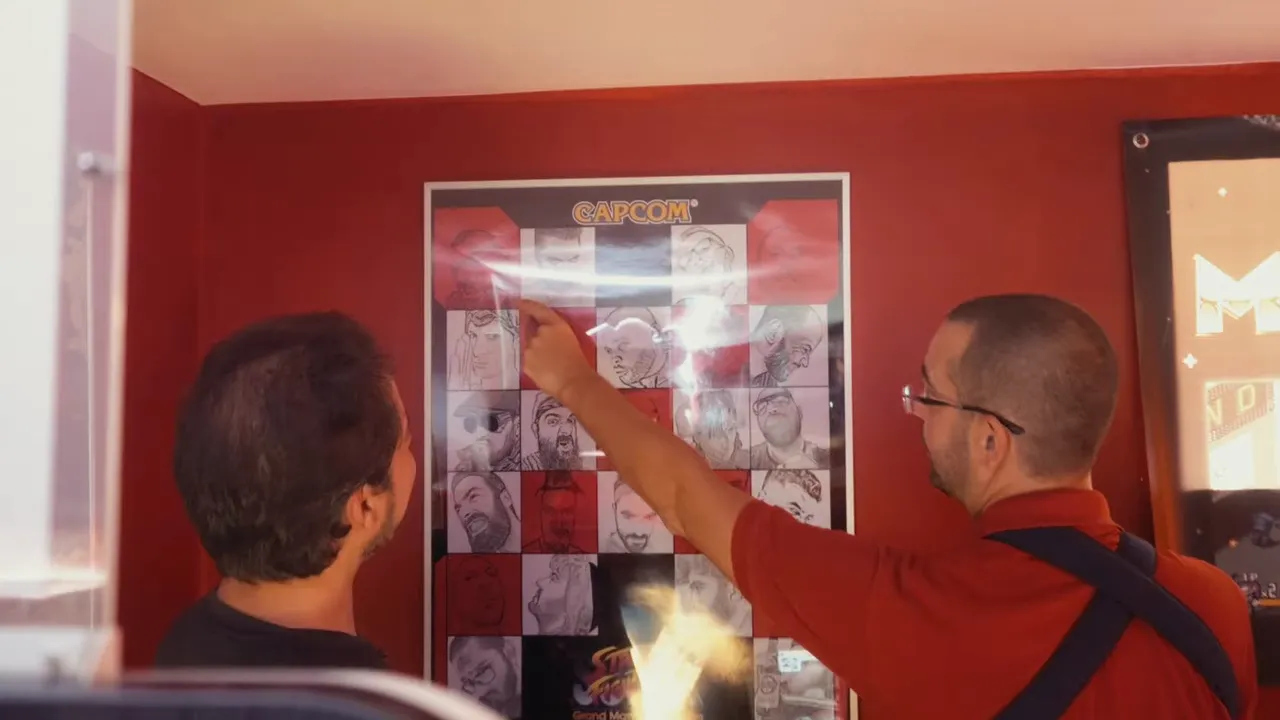 Planche de posters décoratifs dans une salle d’arcade maison, avec un passionné en train de la montrer