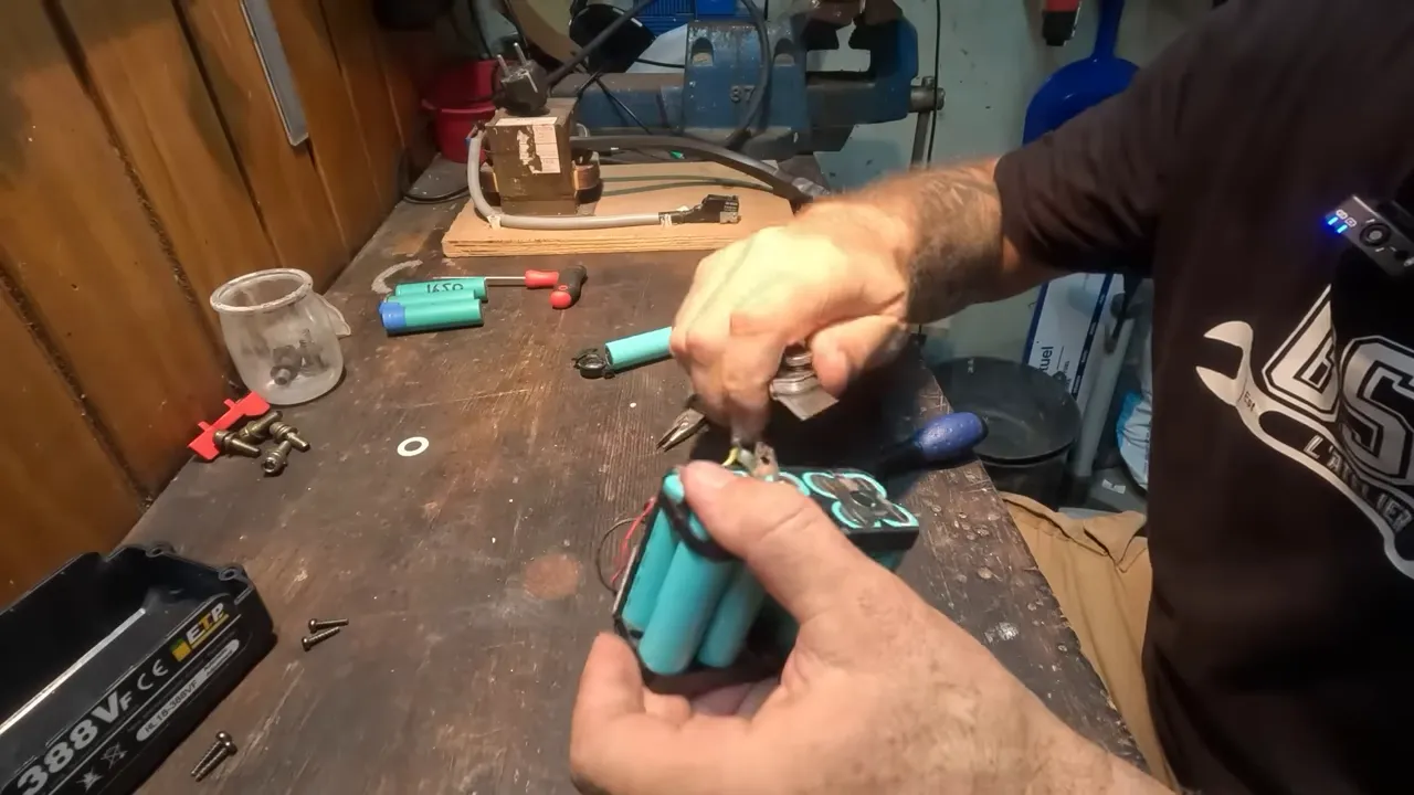 Extraction d'une cellule 18650 défectueuse avec une pince, mains tenant le pack