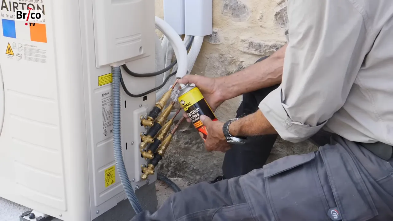 Main pulvérisant un détecteur de fuite sur les raccords frigorifiques de l'unité extérieure