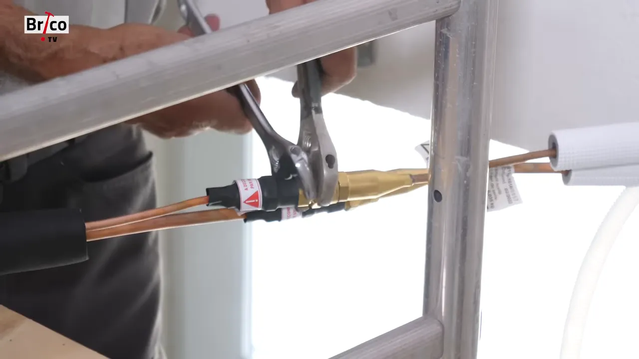 Gros plan sur deux raccords frigorifiques en laiton serrés avec des clés près du mur