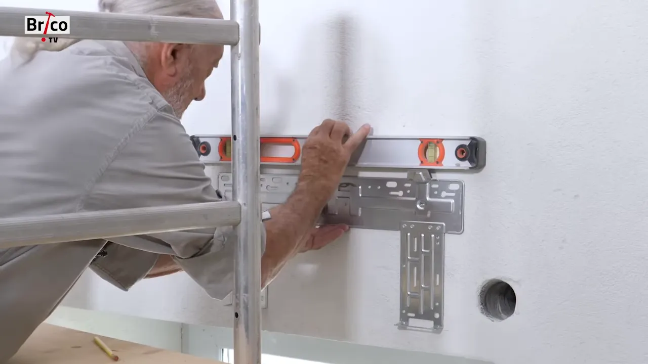 Support métallique d'unité intérieure positionné au niveau à bulle sur un mur blanc avec trou de passage à droite