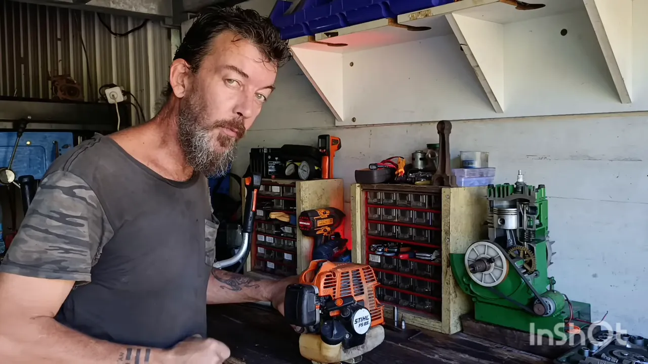 Moteur de débroussailleuse tenu en main pendant le diagnostic en atelier