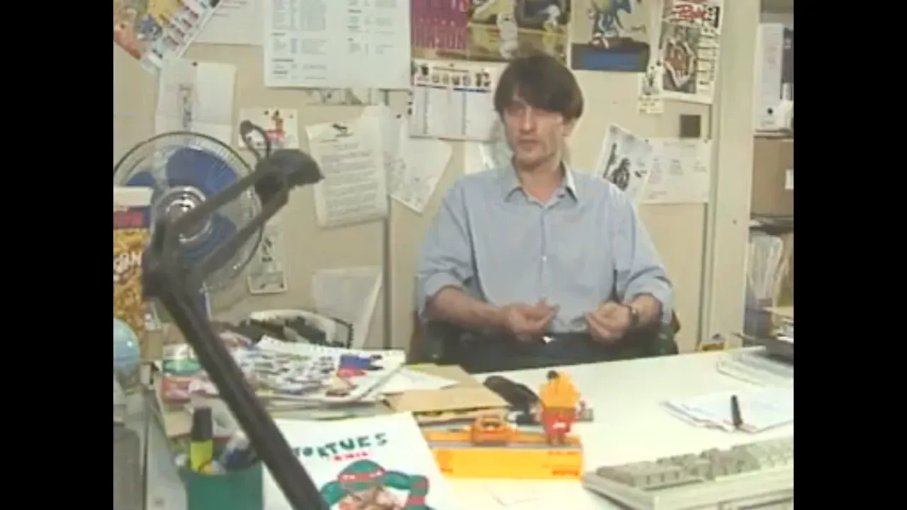 Rédacteur de Player One assis à un bureau couvert de magazines et de documents
