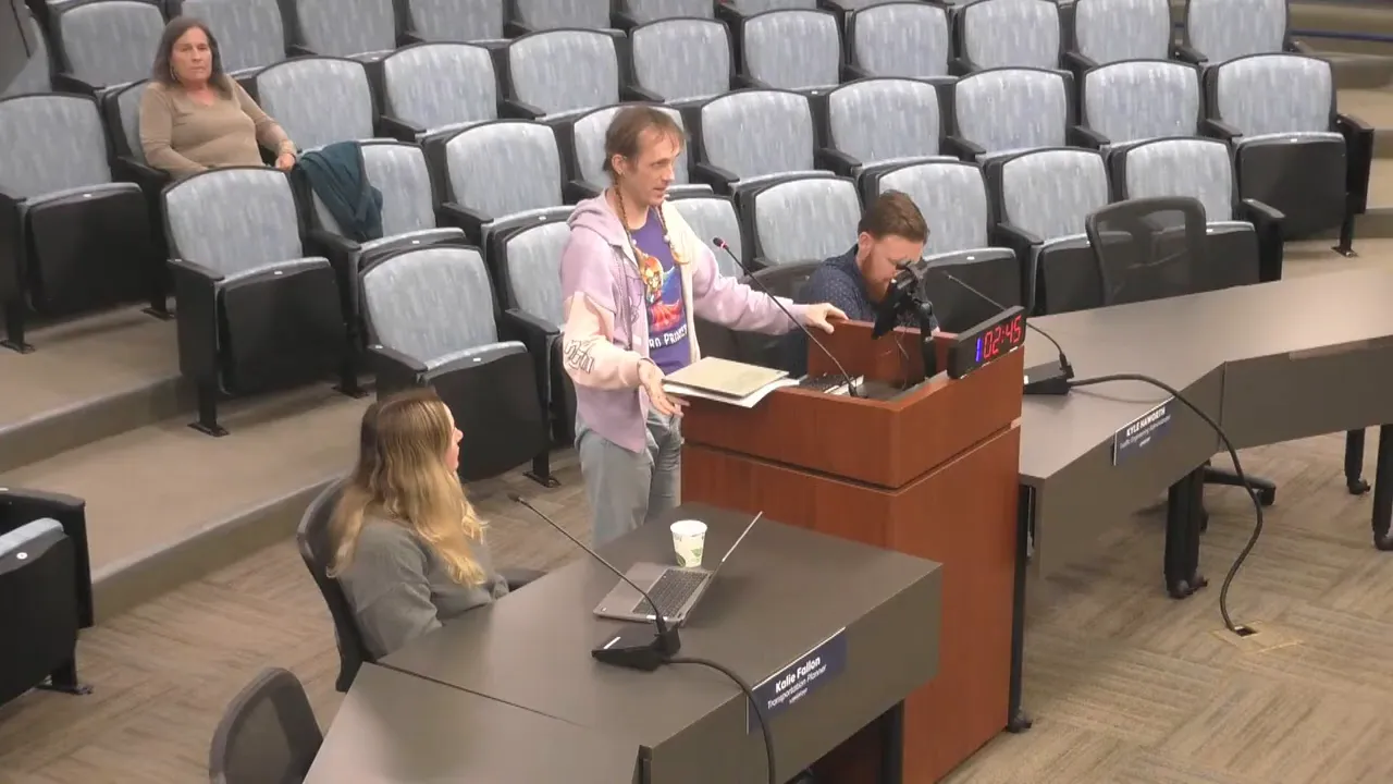 Wide, clear view of a speaker at a meeting podium with empty auditorium seats behind and the lectern timer visible.