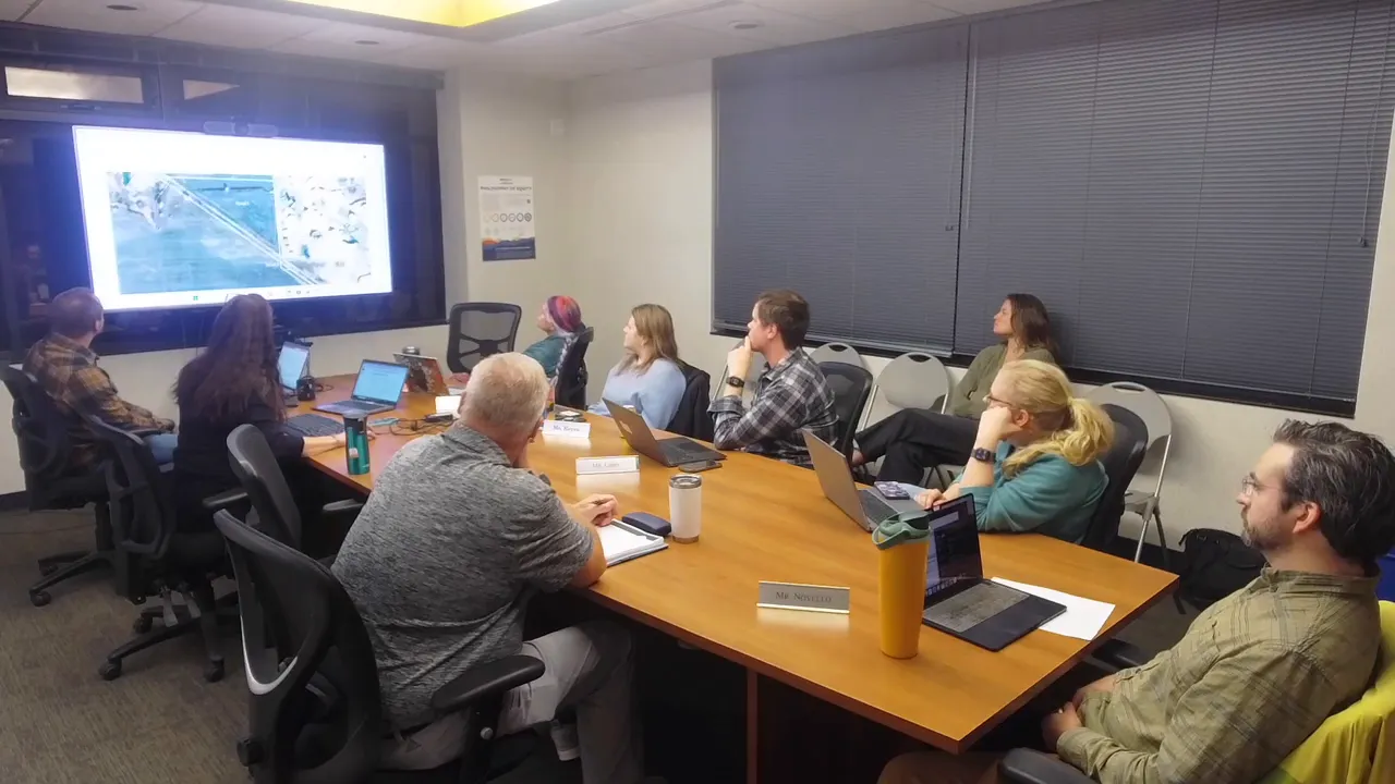 Conference room shot with advisory board viewing a large screen displaying a map of potential Bigelow parcels for acquisition.