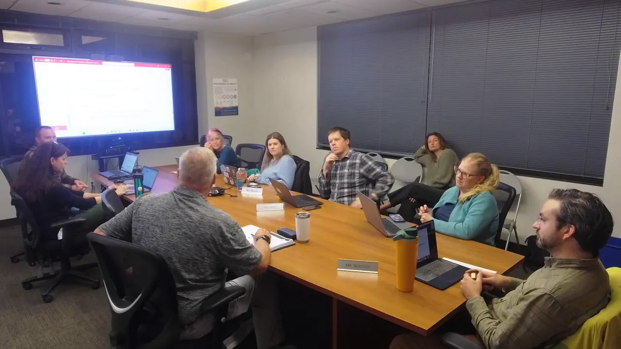 Conference-room view of the parks advisory board with laptops open and attendees focusing on a presentation screen