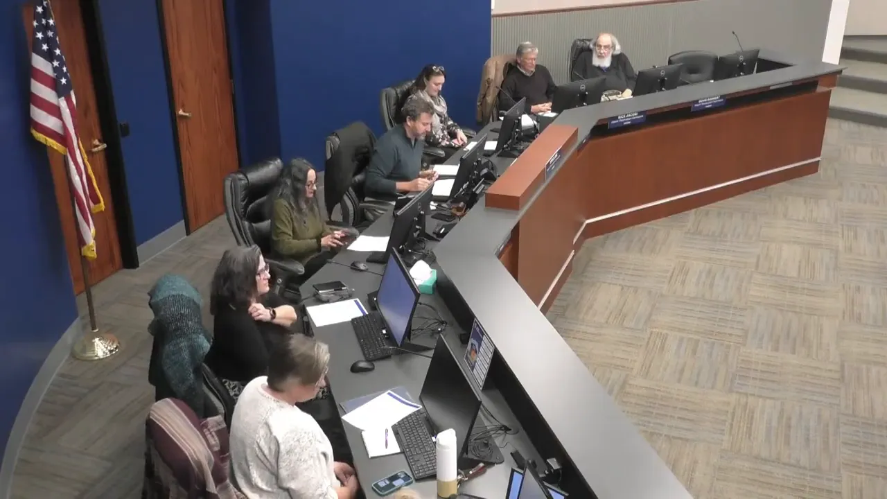 Wide, clear overhead view of the Commission dais with commissioners seated along a curved bench and meeting monitors visible.
