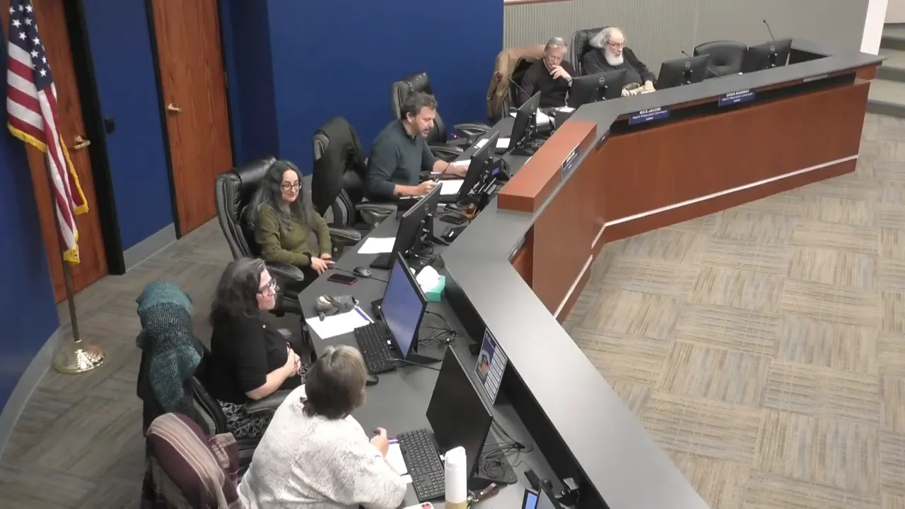 Clear image of commissioners at the dais with the chair addressing the meeting and members at computers.