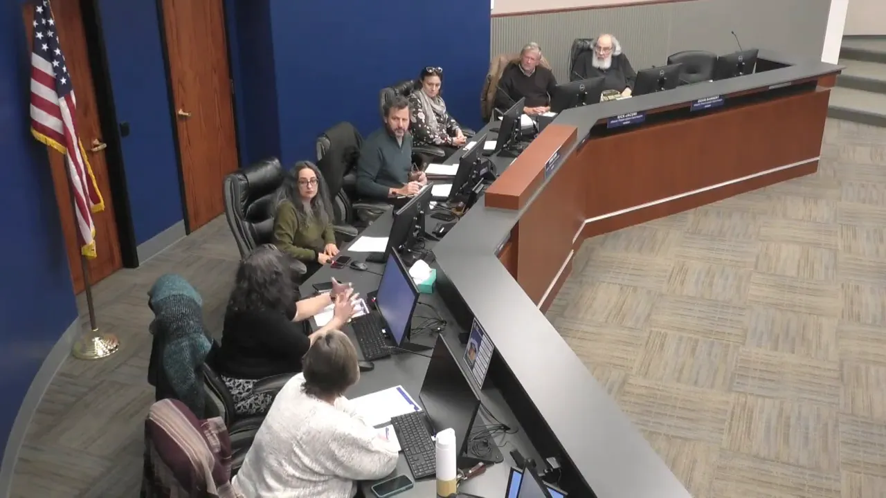 Wide overhead view of Historic Preservation Commission members seated around a curved dais, consulting documents and monitors during a public meeting.