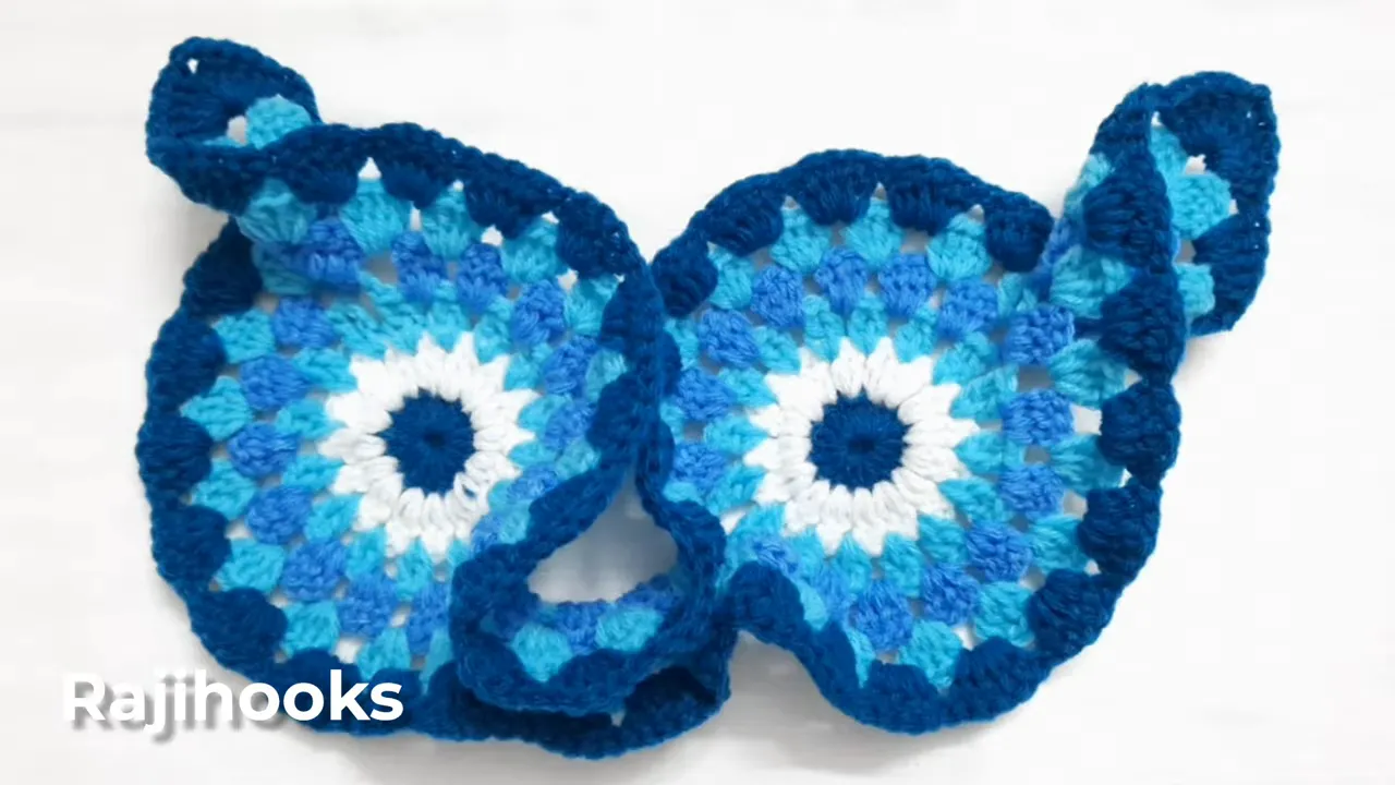 Two joined blue crochet motifs with dark blue scalloped borders and curled end sections
