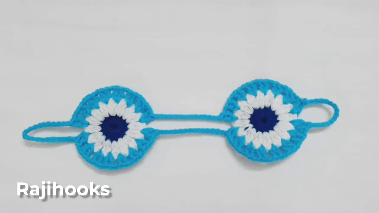 Two turquoise-edged crochet circles connected by parallel chains with loops at both outer ends