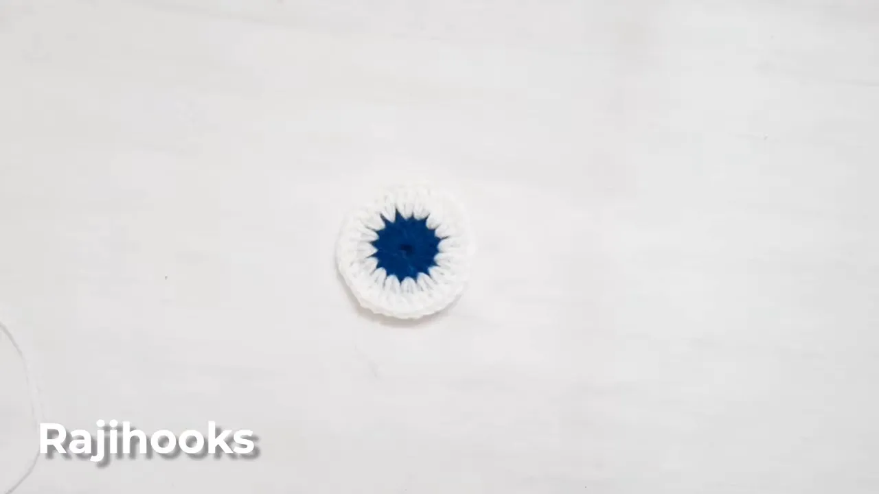 Two crochet circles with dark blue centers and white outer rounds on a white surface
