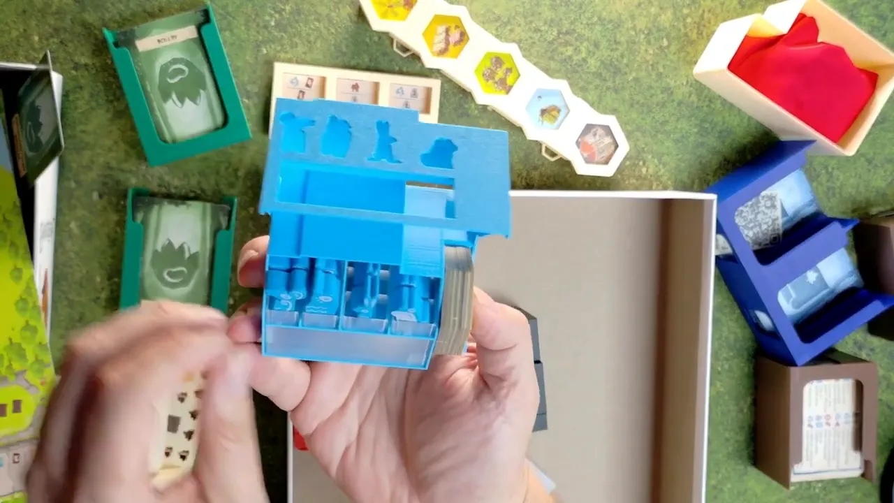 Geöffnete blaue Spielerbox mit mehreren Fächern und aufrecht stehenden kleinen Spielfiguren