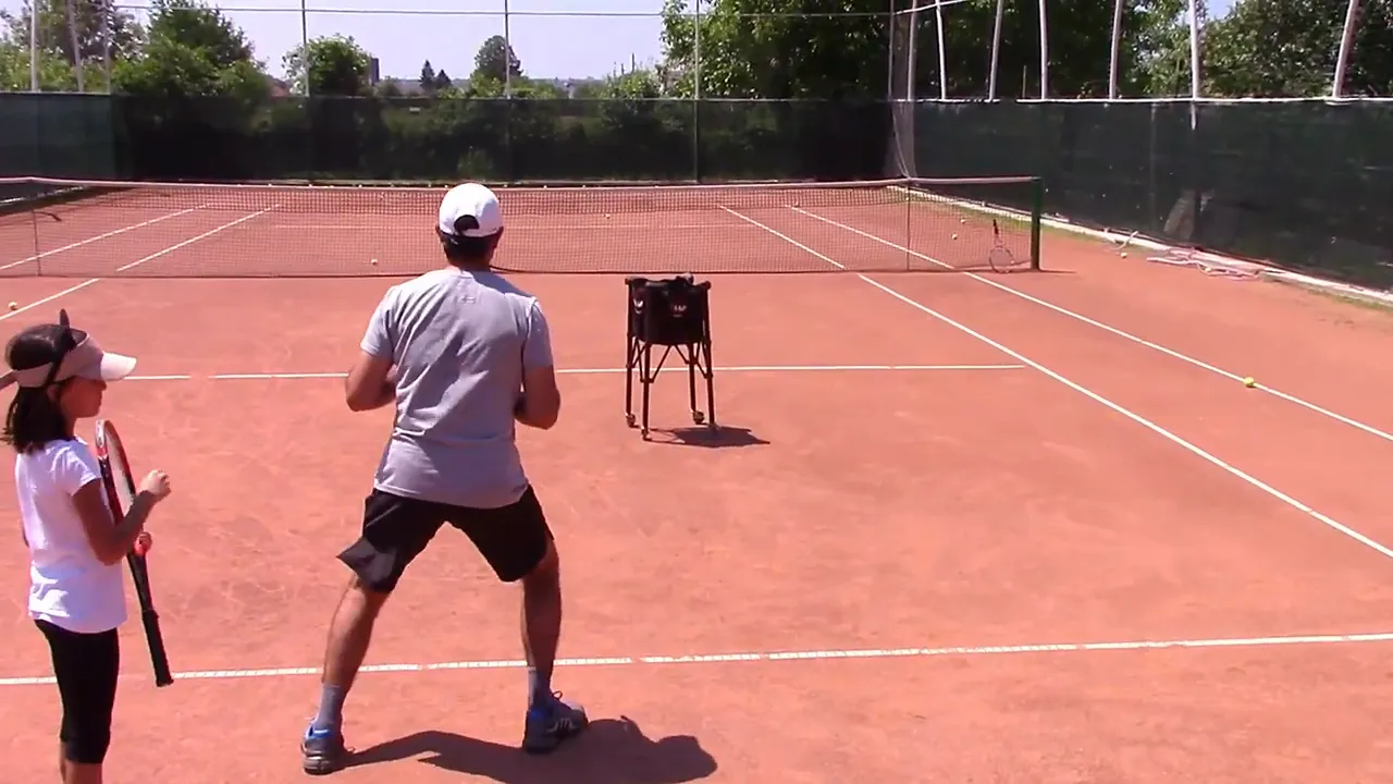 Coach demonstrating lateral footwork with bent knees while Bianca stands nearby