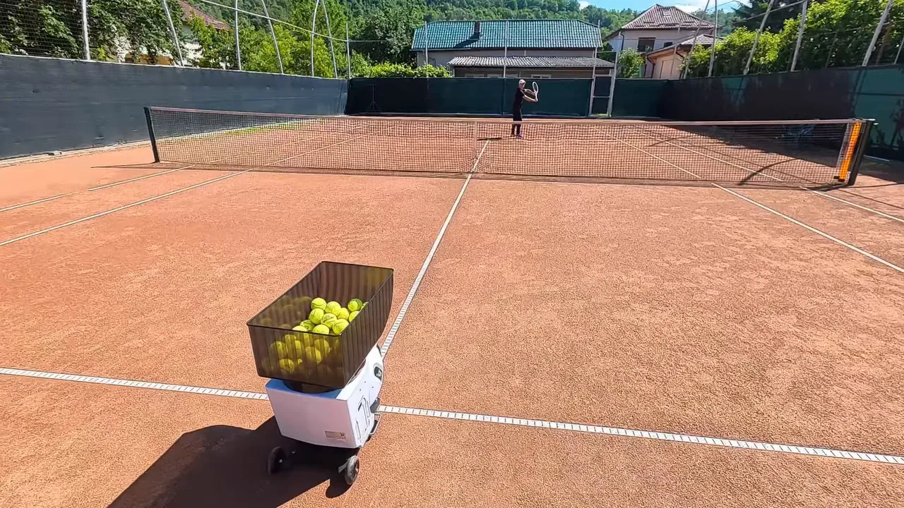 ball machine loaded with yellow balls placed on the court near the service line