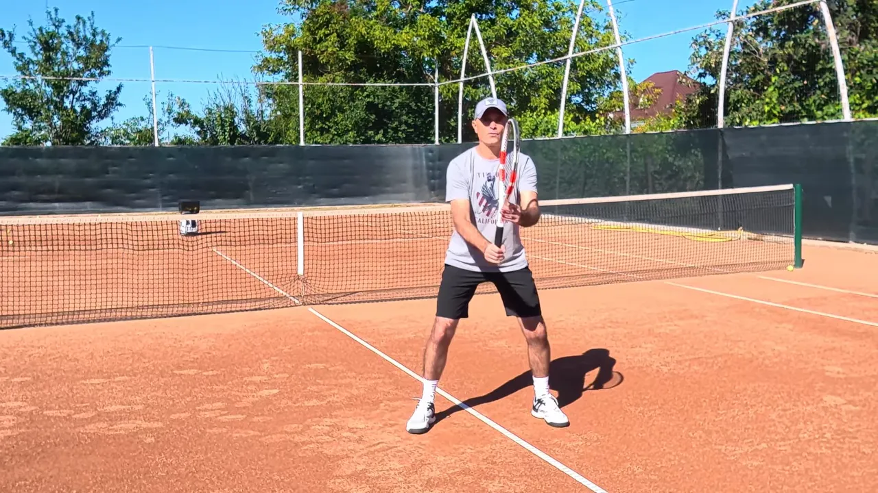 Coach in a low ready position with feet apart and racquet held in front