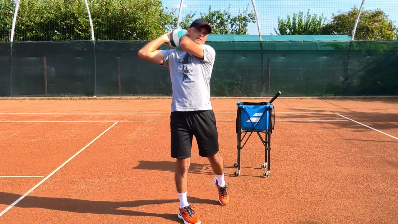 Coach holding a volleyball with both hands beside his shoulder on a tennis court