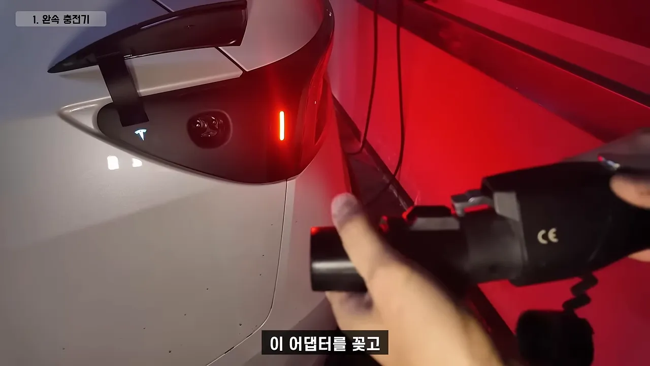 테슬라 충전 포트 앞에서 완속 충전기 커넥터와 어댑터를 연결하는 모습
