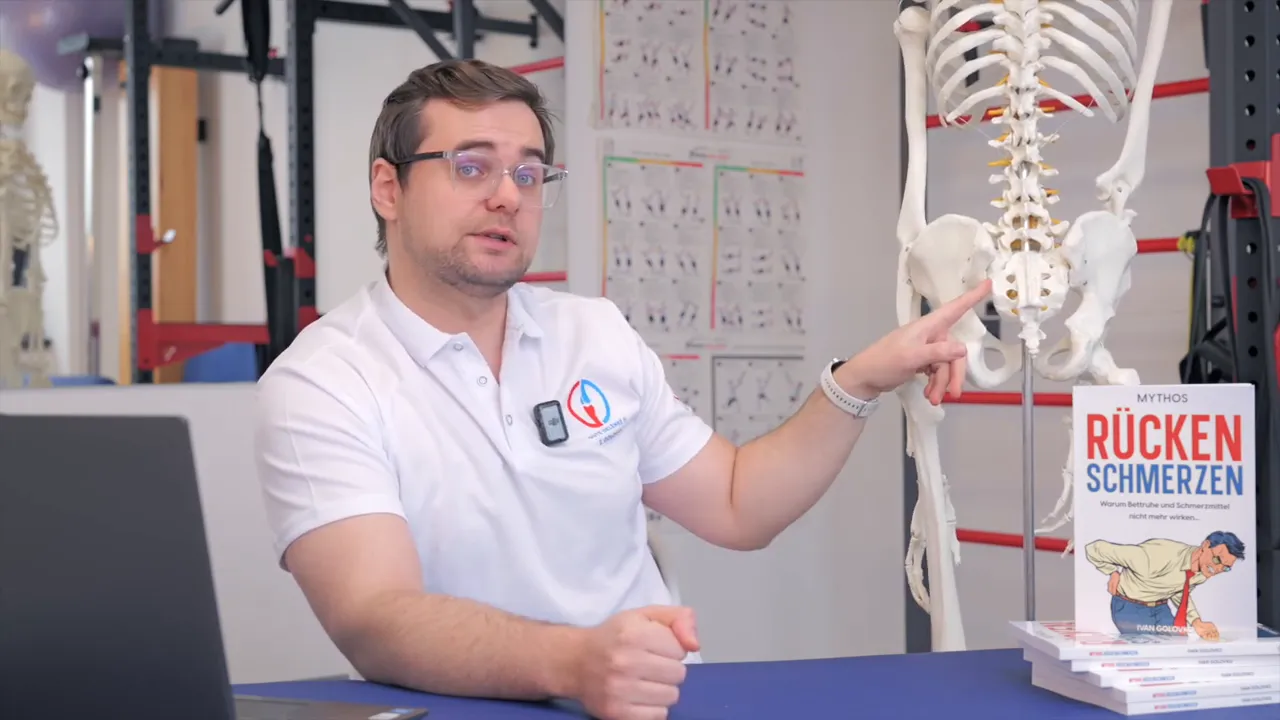 Therapeut zeigt mit dem Finger auf das Kreuzbein/ISG am anatomischen Skelettmodell zur Veranschaulichung der Kompensationskette