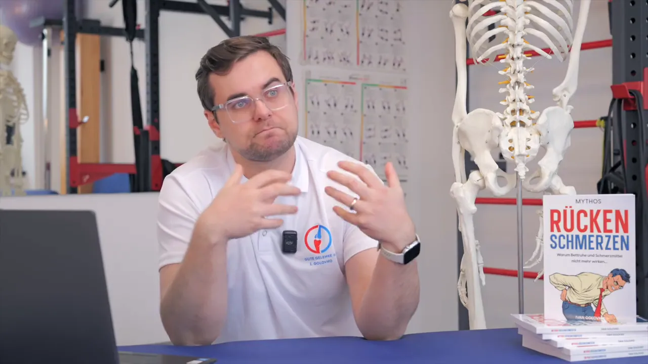 Physiotherapeut gestikuliert intensiv neben einem anatomischen Skelettmodell und dem Buch 'Rücken Schmerzen'