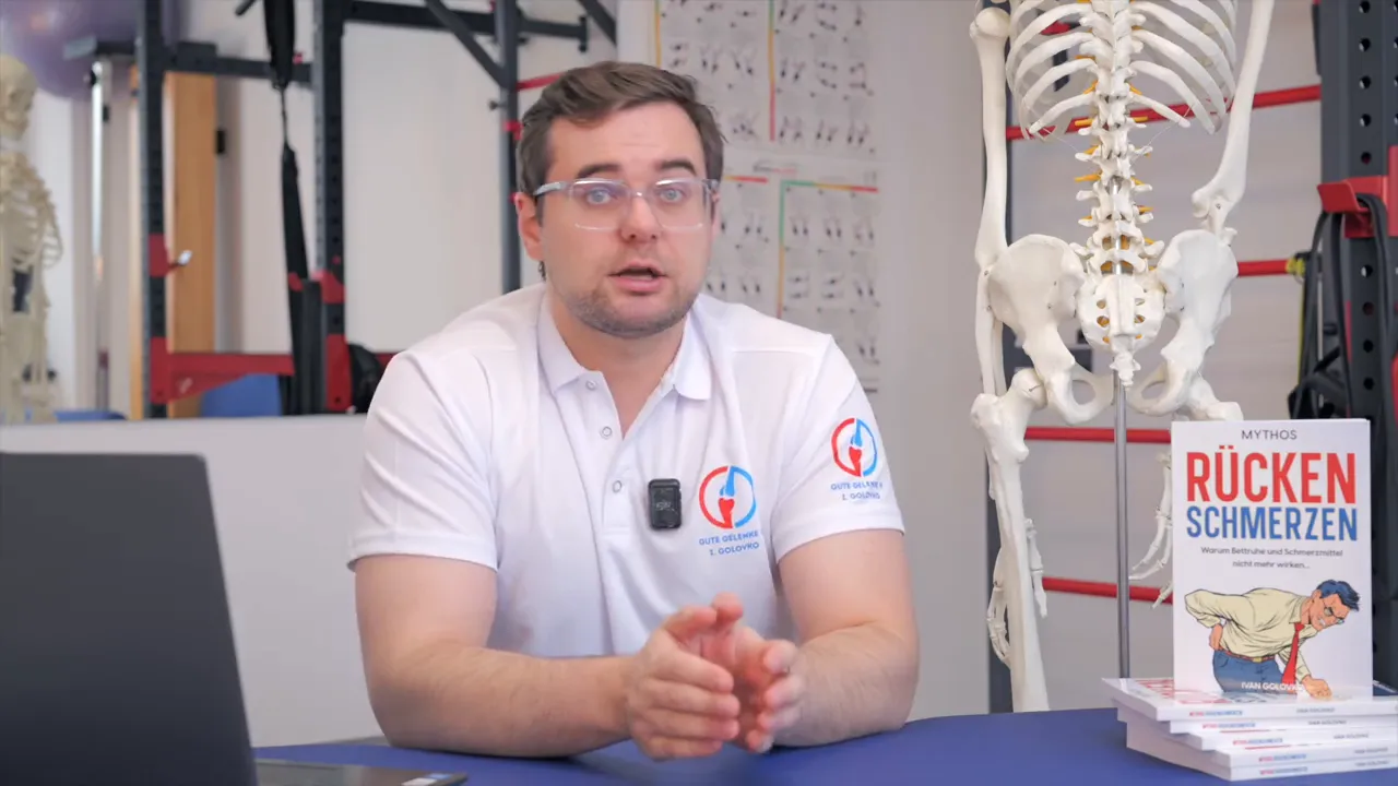 Physiotherapeut spricht erklärend neben Skelettmodell und Stapel Bücher 'Rückenschmerzen'