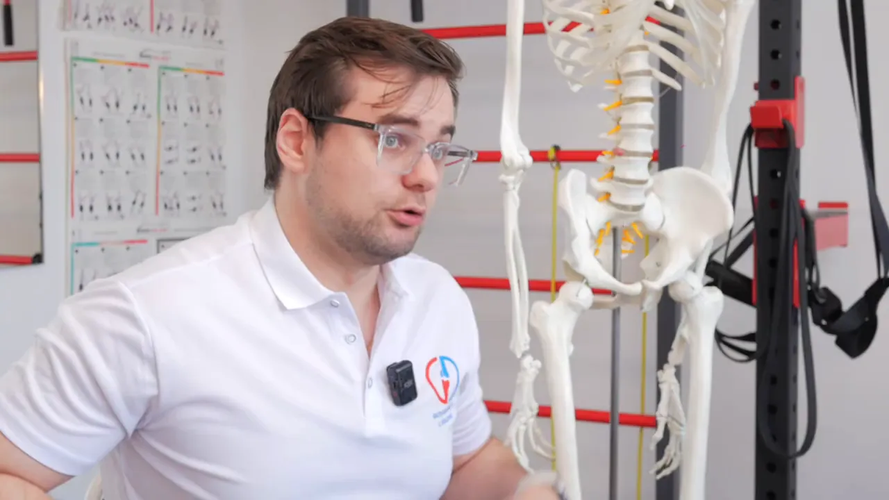 Physiotherapeut erklärt neben Skelettmodell mit sichtbarem Becken und gelben Nervenwurzeln