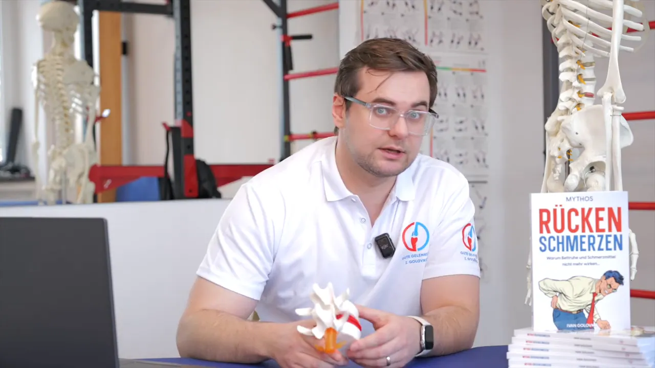 Physiotherapeut hält Wirbelsäulenmodell und erklärt Warnzeichen bei Ischias