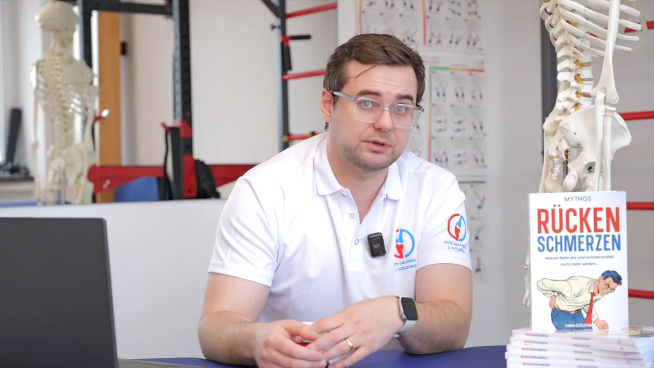 Physiotherapeut erklärt Behandlung und zeigt Wirbelsäulenmodell neben Buch zu Rückenschmerzen