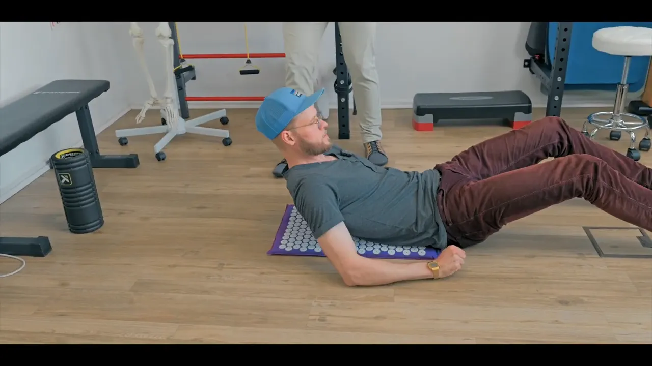 Moderator liegt rücklings auf einer lila Shiatsu‑Matte, die Noppenauflage liegt am Rücken zur Demonstration.