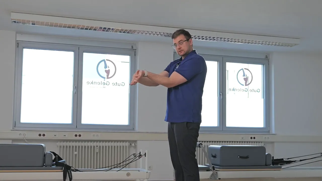 Therapeut demonstriert dynamische Ellenbogenbeugung mit Daumendruck an der Innenseite des Ellenbogens