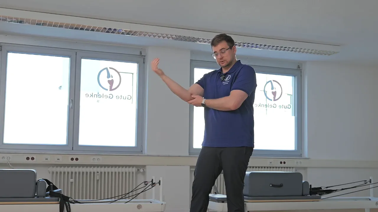 Therapeut demonstriert lokale Druckmassage am inneren Ellenbogen mit Daumenkontakt und Bewegung