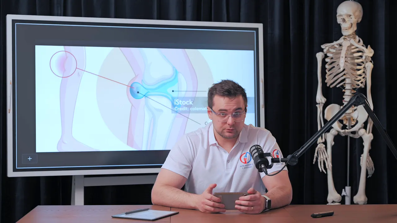 Referent vor Bildschirm mit schematischer Knie‑Grafik, die eine Bakerzyste in der Kniekehle zeigt