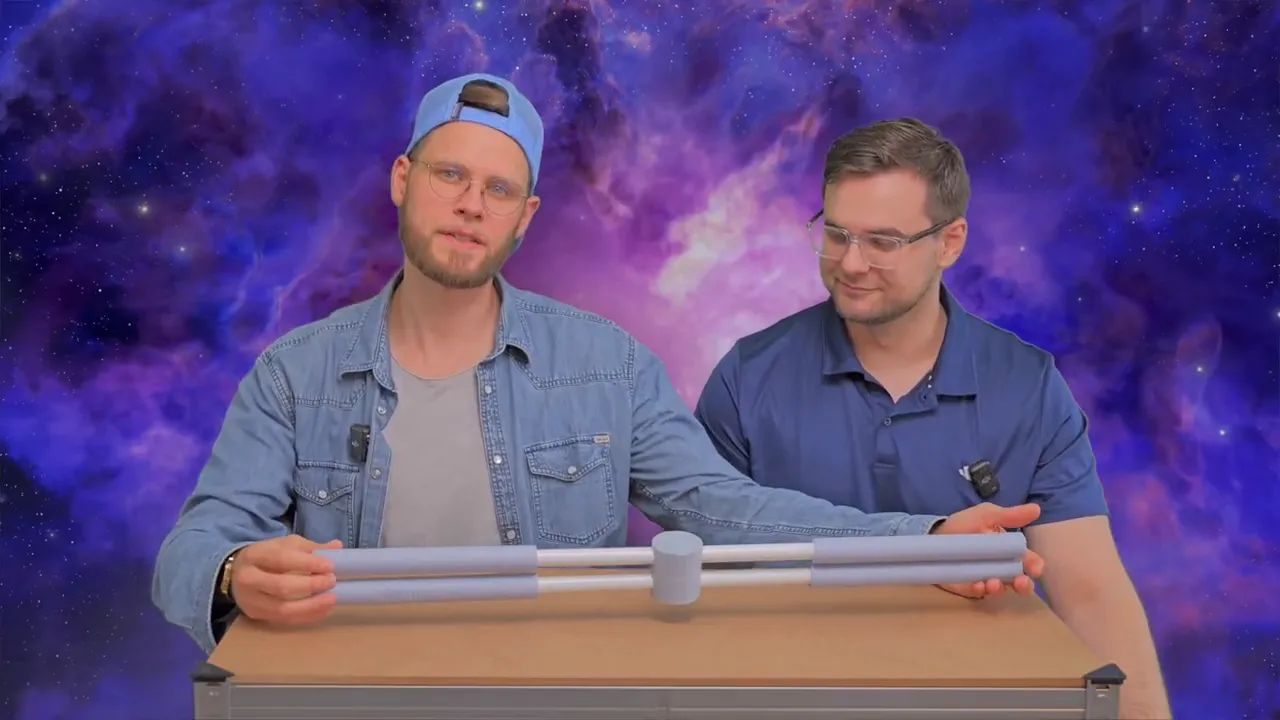 Zwei Personen, eine hält den Haltungstrainer horizontal vor die Kamera und erklärt Aufbau und Polsterungen.