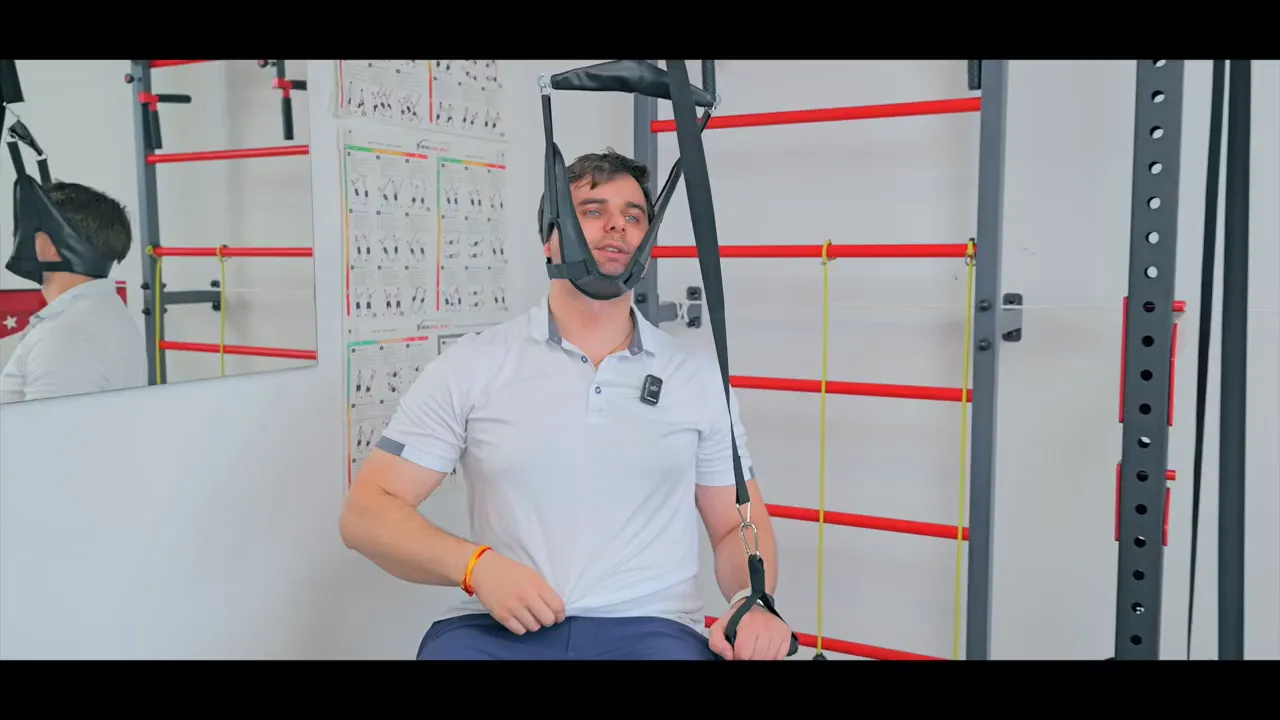 Person sitzt in einer Nackentraktionsschlinge, angeschlagen an einem Trainingsgestell, ganze Szene sichtbar