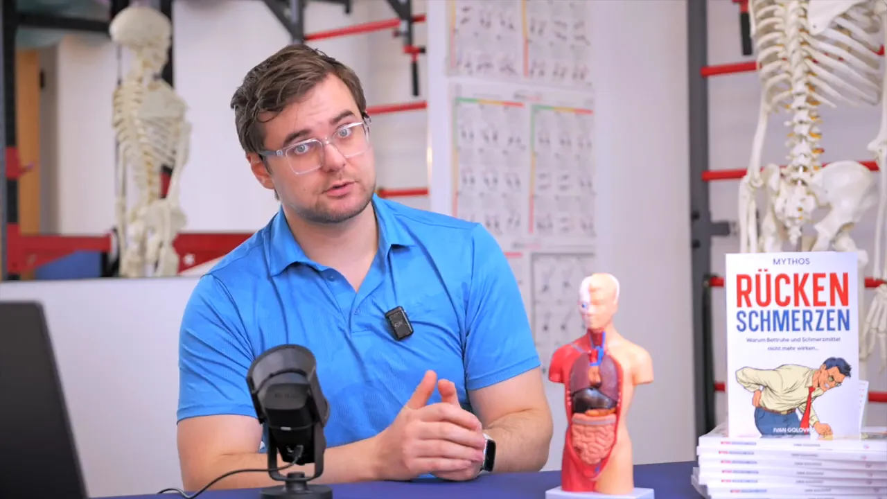 Physiotherapeut erläutert Schlaf und Regeneration neben Anatomiemodell und Buch 'Rückenschmerzen'