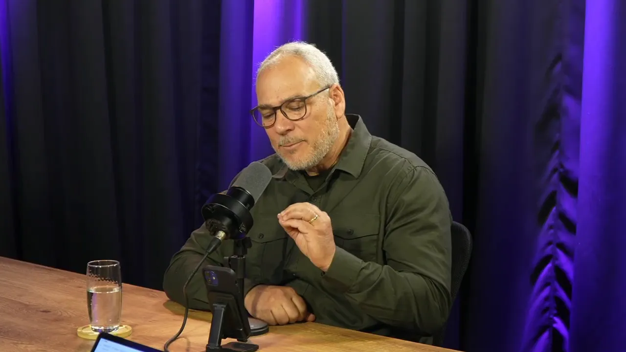 Instrutor fazendo um gesto explicativo preciso com os dedos enquanto fala ao microfone durante treino de oratória