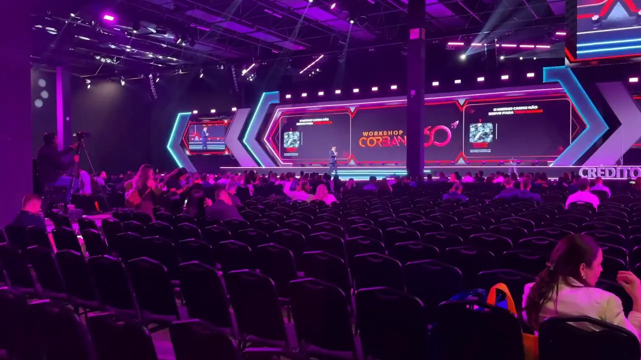 Plateia na plenária do Corban 360 com palco e telões iluminados