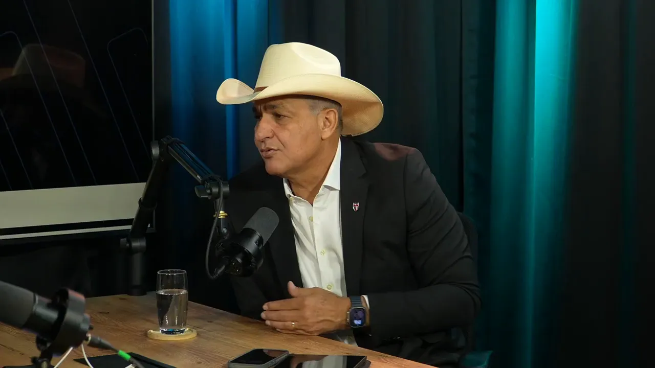 homem de chapéu branco gesticulando enquanto fala em estúdio de podcast